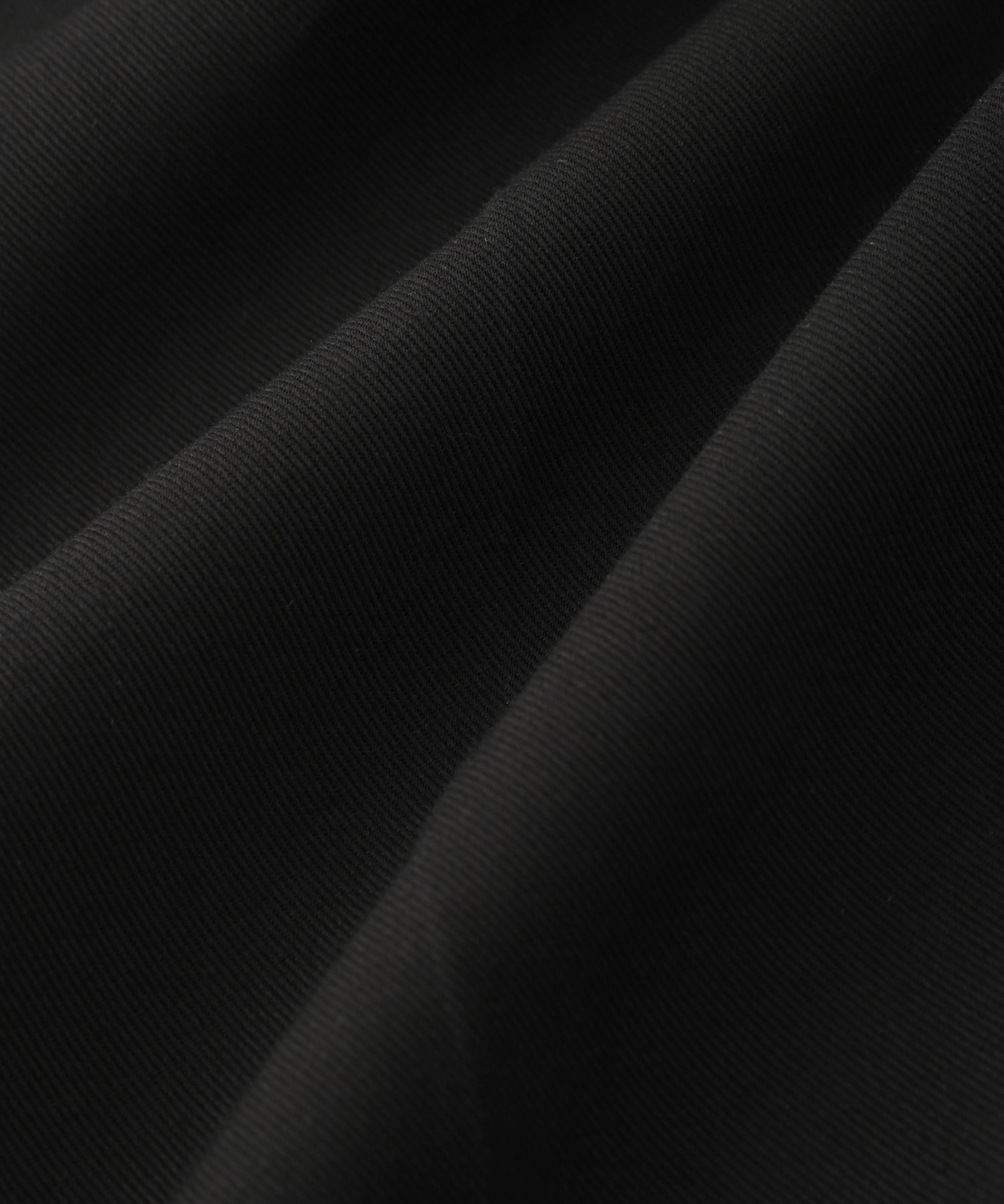 Saturdays NYC. 1Tuck Tapered Pants. Close-up of the high-twisted cotton fabric, showcasing the crisp texture and refined finish, in black.