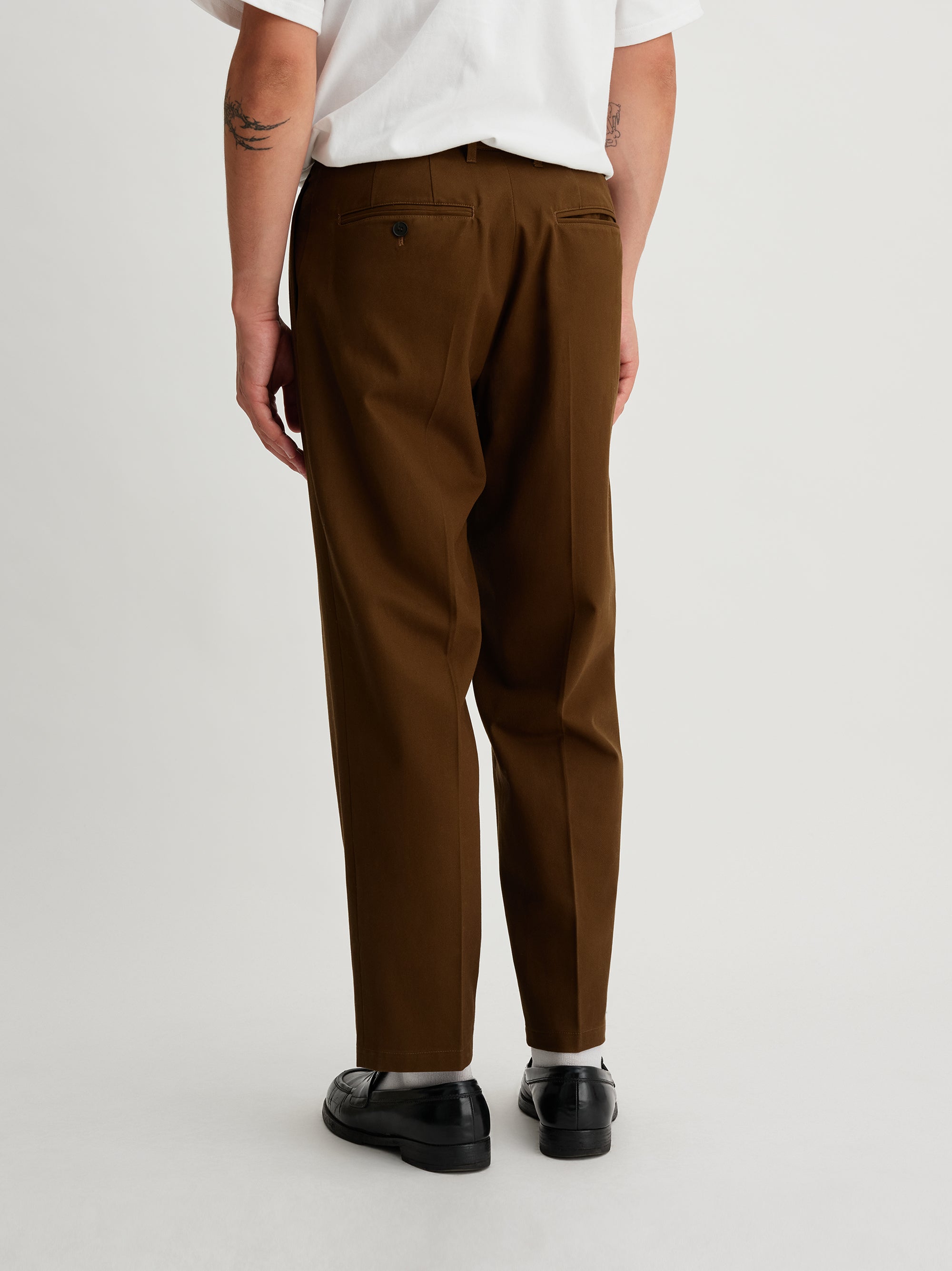 Saturdays NYC. 1Tuck Tapered Pants. Back view of model wearing the khaki chinos, showcasing the tailored fit, relaxed silhouette, and clean back design.